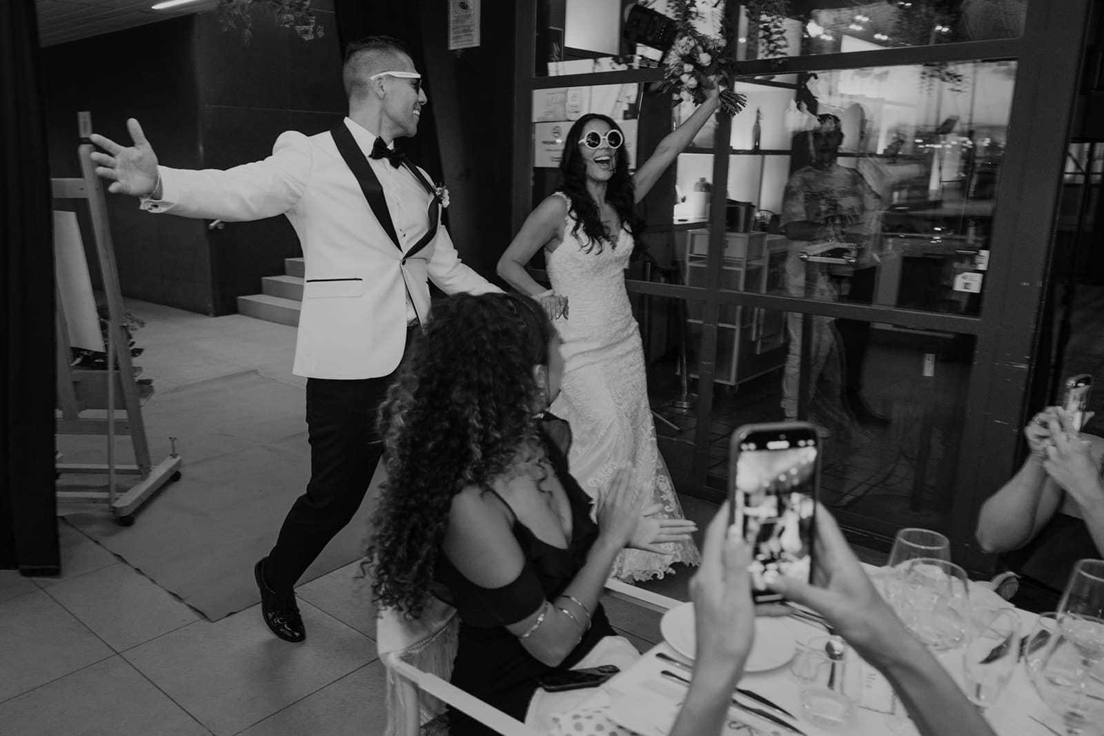Couple entering their destination wedding reception surrounded by cheering family and friends in Europe.